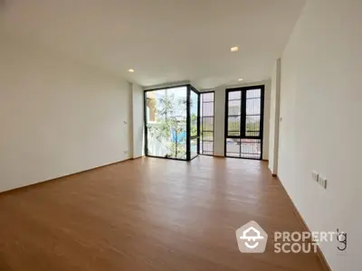 Spacious living room with natural light, hardwood floors, and a charming balcony with a protective railing, perfect for modern urban living.