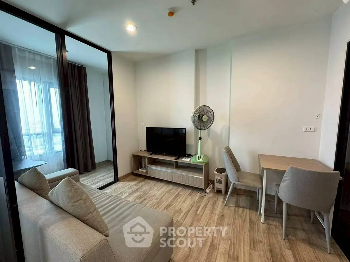 Modern living room with cozy sofa, TV, and dining area in open layout apartment.