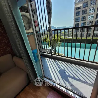 Modern apartment with balcony overlooking pool and cityscape, featuring cozy interior and abundant natural light.