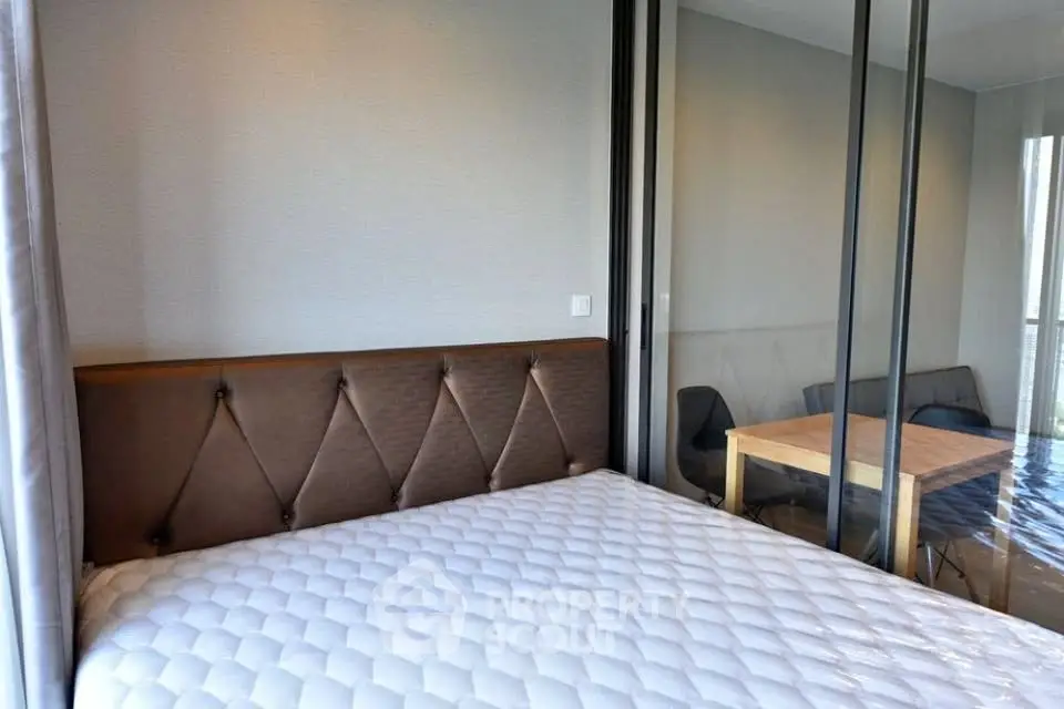 Modern bedroom with stylish headboard and glass partition leading to a cozy dining area.
