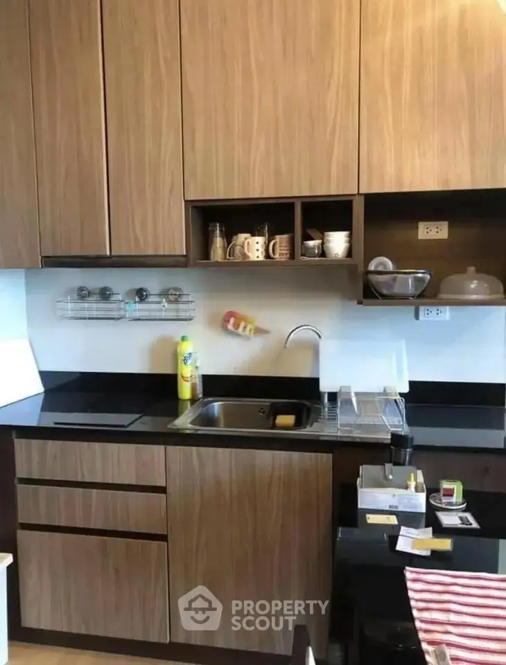 Modern kitchen with sleek wooden cabinets and black countertops, featuring a compact and efficient design.