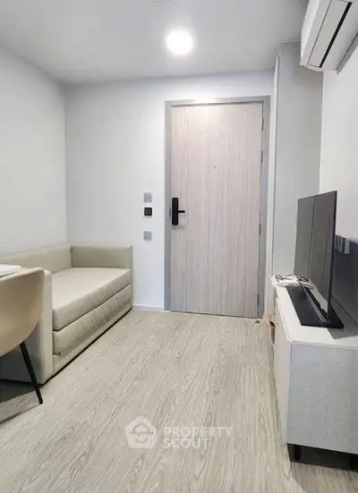 Modern minimalist living room with sleek furniture and neutral tones, featuring a cozy sofa and flat-screen TV.