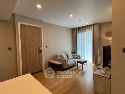 Modern living room with cozy sofa and wooden flooring, featuring natural light from large window.