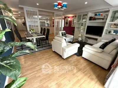 Spacious living room with elegant decor and open dining area, featuring modern lighting and hardwood floors.