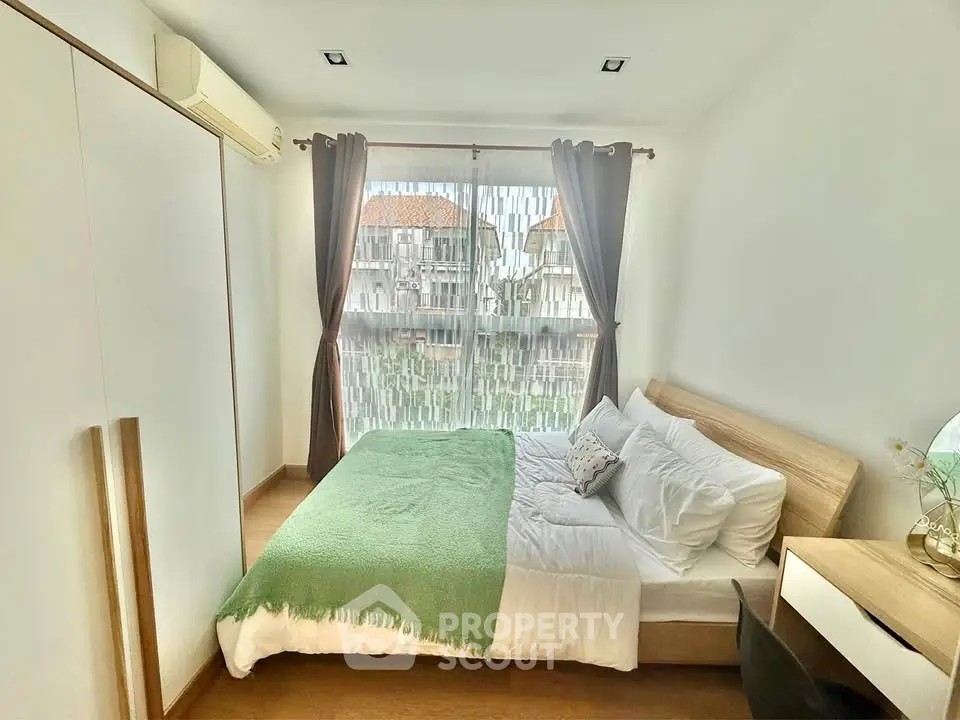 Cozy bedroom with large window and modern decor in a stylish apartment.
