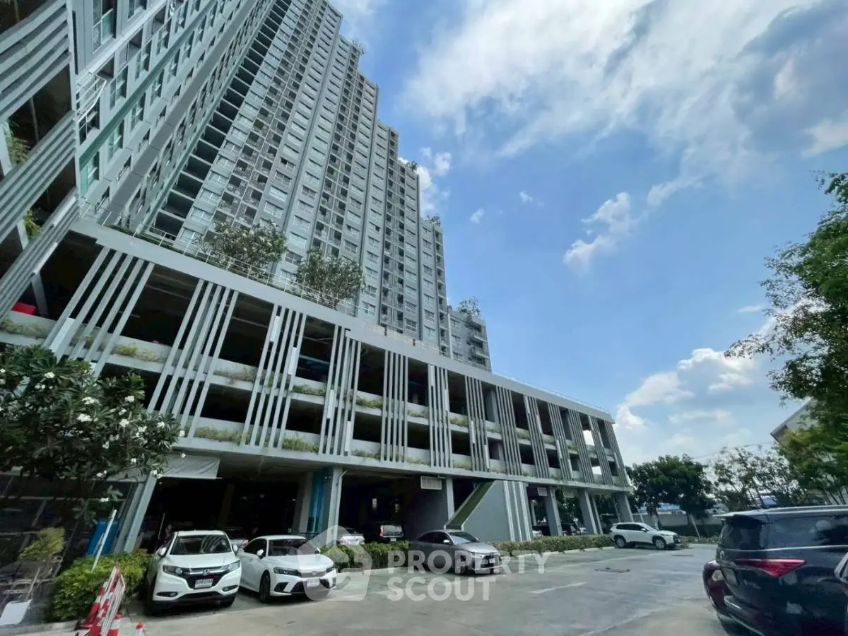 Modern high-rise building with parking area and clear blue sky