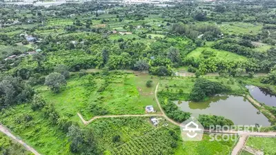 Expansive aerial view of lush green land with ponds, ideal for development opportunities.