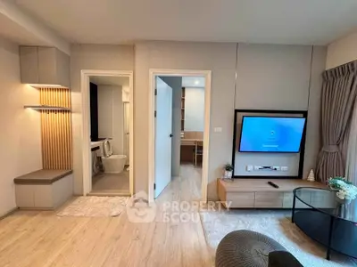 Modern living room with TV, stylish decor, and open view into bathroom and study area.