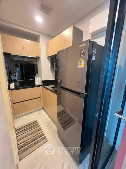 Modern kitchen with sleek appliances and wooden cabinetry in a compact layout.