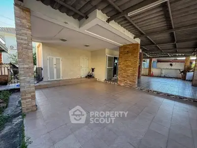 Spacious covered patio with tiled flooring and brick accents, perfect for outdoor gatherings.