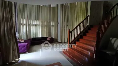 Elegant living room with grand staircase and floor-to-ceiling curtains