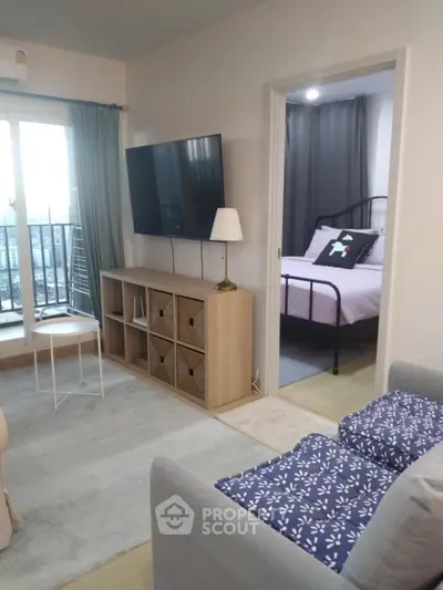 Modern living room with TV, cozy bedroom, and balcony access in stylish apartment.