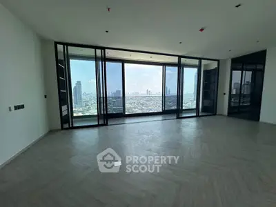 Spacious modern living room with floor-to-ceiling windows offering stunning city skyline views.
