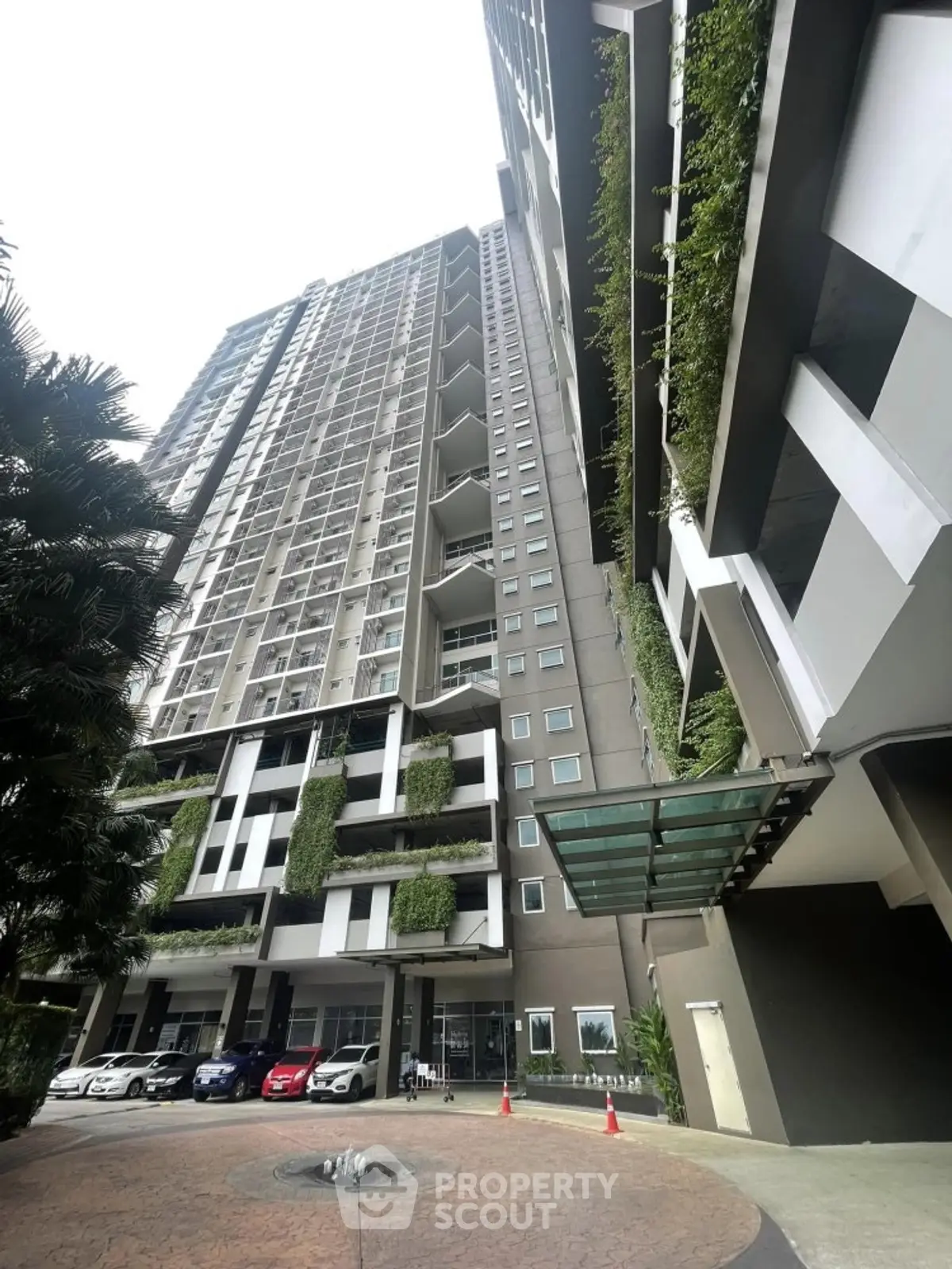 Modern high-rise building with lush greenery and spacious balconies in urban setting.