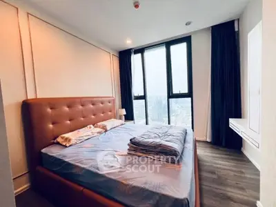 Spacious bedroom with large windows offering stunning city views and modern decor.