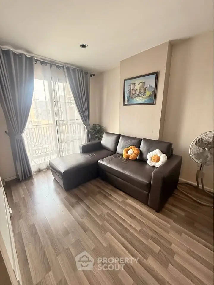Cozy living room with modern sofa and natural light from large windows.