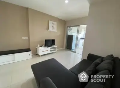 Modern living room with sleek black sofa and wall-mounted TV in a bright apartment.