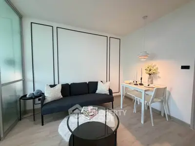 Modern living room with sleek black sofa, stylish dining area, and contemporary decor.