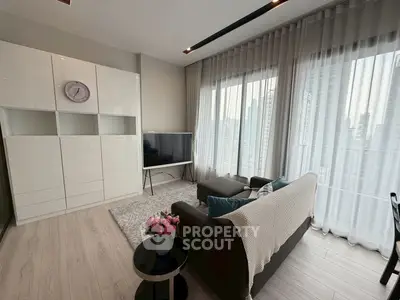 Modern living room with sleek furniture and large windows offering city views.