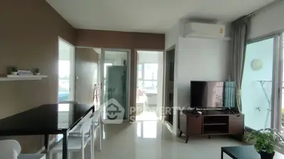 Modern living room with dining area, TV, and large windows offering natural light and city views.