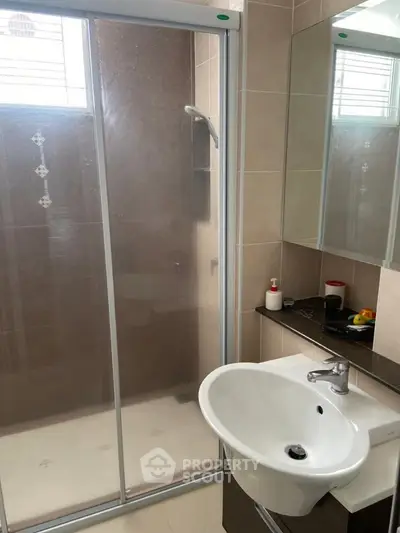 Modern bathroom with glass shower enclosure and sleek sink design.