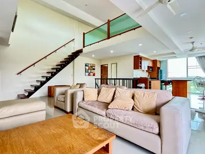 Spacious modern living room with open layout and stylish staircase in a luxury apartment.
