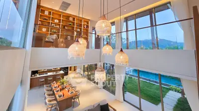 Luxurious open-plan living room with high ceilings, elegant lighting, and pool view, perfect for modern living.