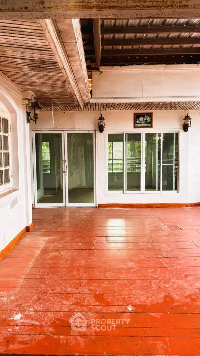 Spacious balcony with red wooden flooring and sliding glass doors, perfect for outdoor relaxation.