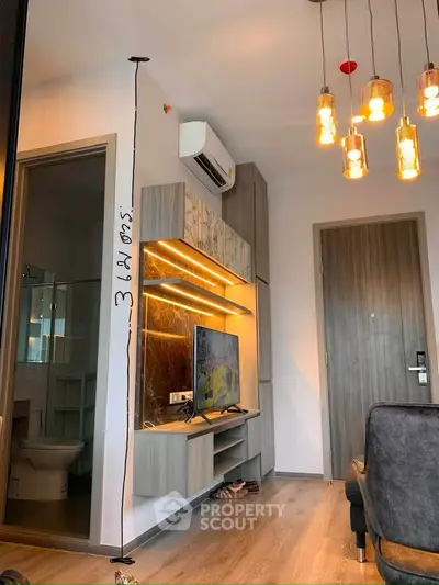 Modern living room with stylish lighting and wall-mounted TV in a cozy apartment.