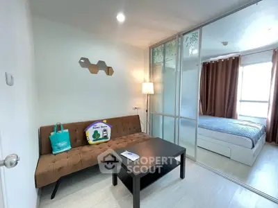 Modern apartment with cozy living room and stylish bedroom separated by glass partition.