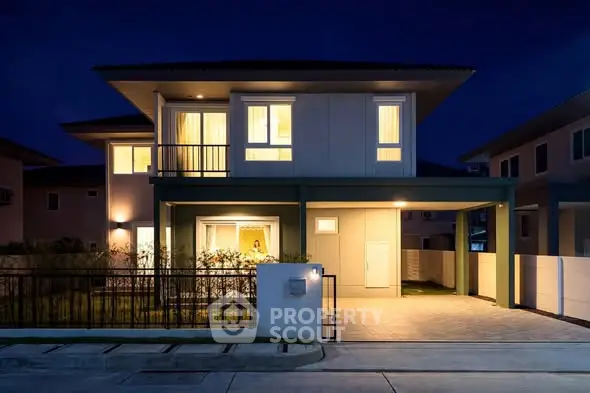 Modern two-story house with illuminated windows and spacious driveway at night.