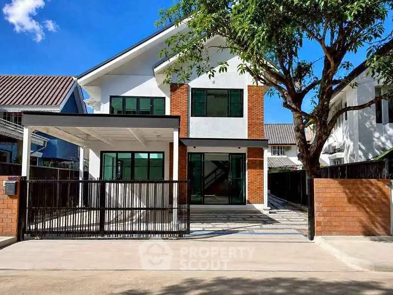 Modern two-story house with brick accents and spacious driveway under clear blue sky.