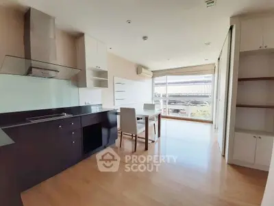Modern open-layout kitchen with sleek cabinetry and dining area, featuring large windows for natural light.