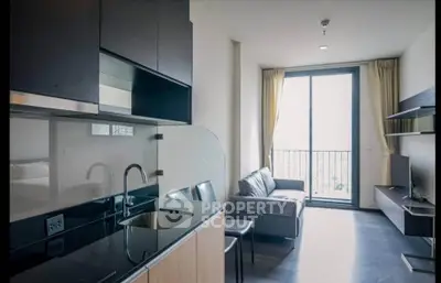 Modern apartment interior with sleek kitchen and cozy living area, featuring large windows and natural light.