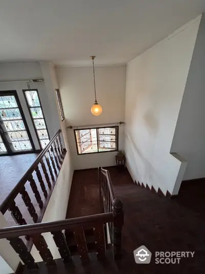 Elegant staircase with wooden railing and large windows in spacious home