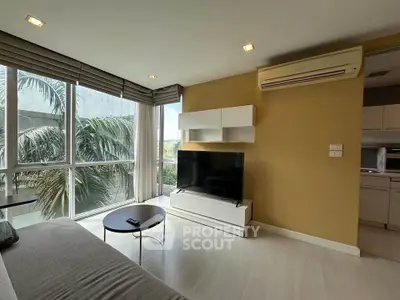 Modern living room with large windows and air conditioning, featuring a sleek TV setup and stylish decor.