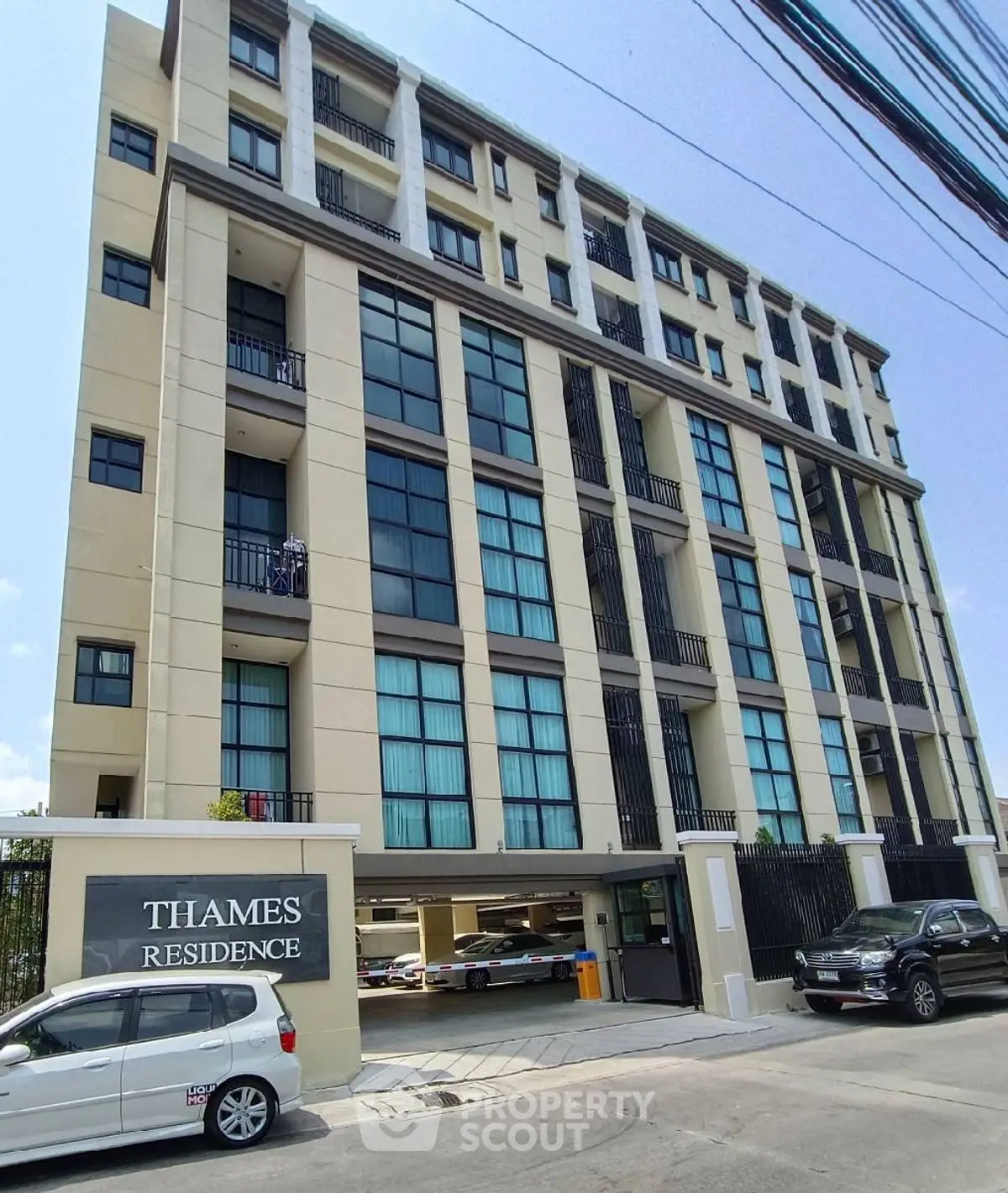Modern multi-story residential building with parking area and sleek facade.