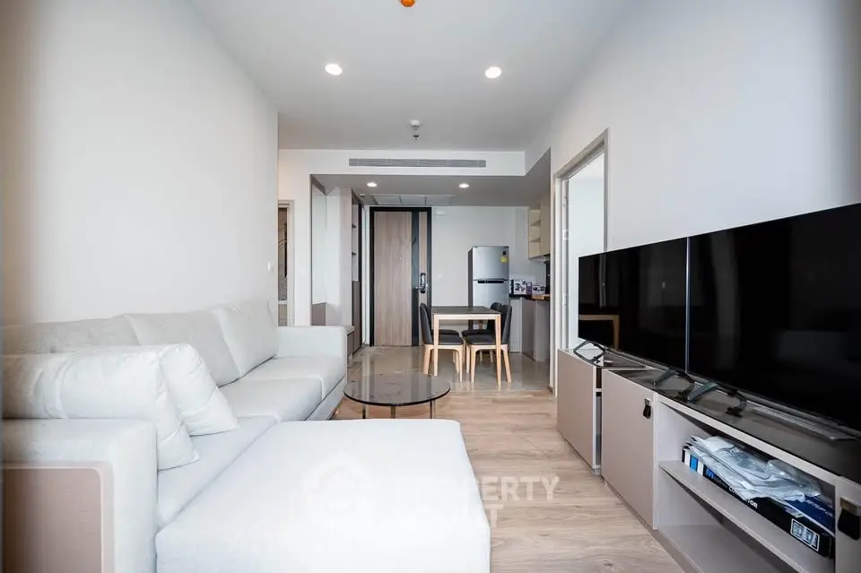 Modern living room with sleek furniture and open kitchen layout in a stylish apartment.