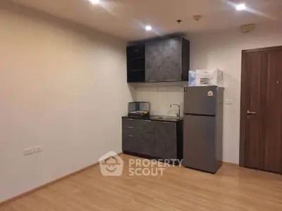 Modern compact kitchen with sleek cabinets and stainless steel fridge in cozy apartment.