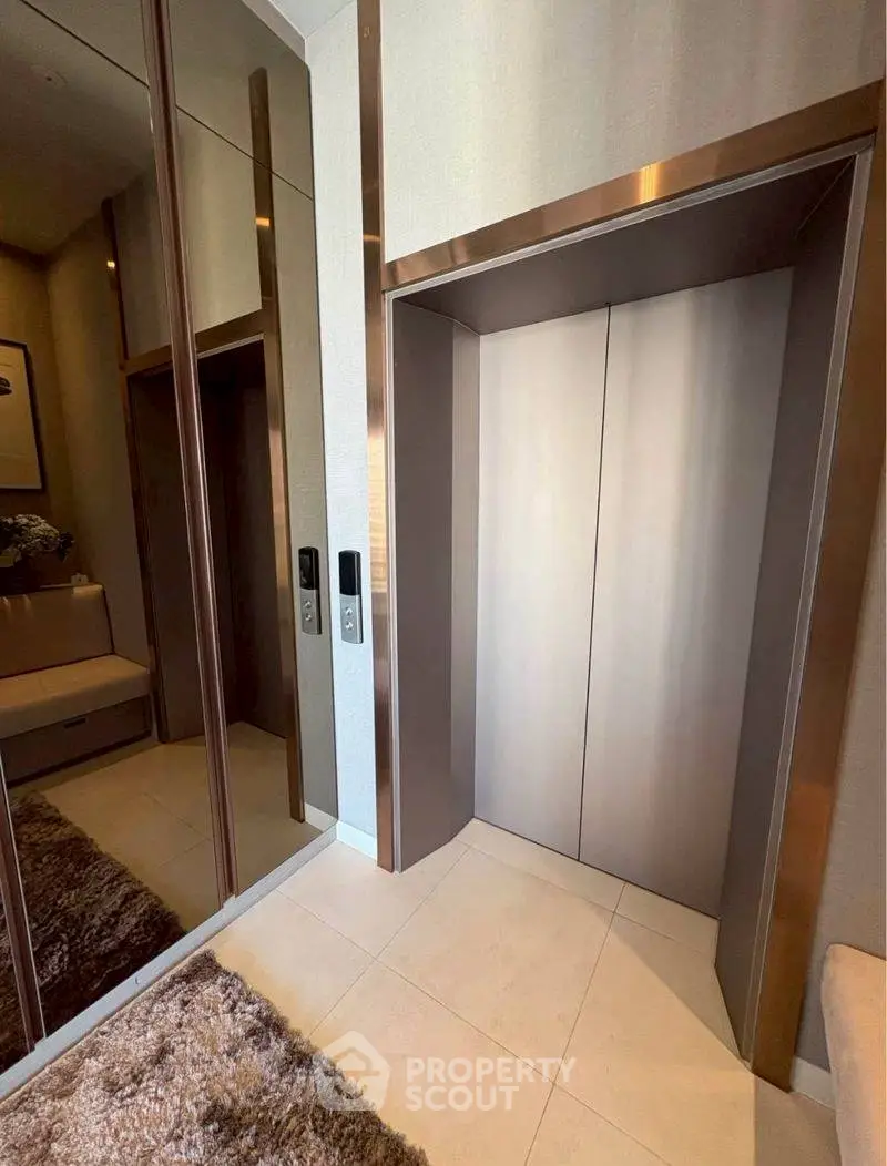 Modern elevator lobby with sleek design and mirrored walls in luxury building.