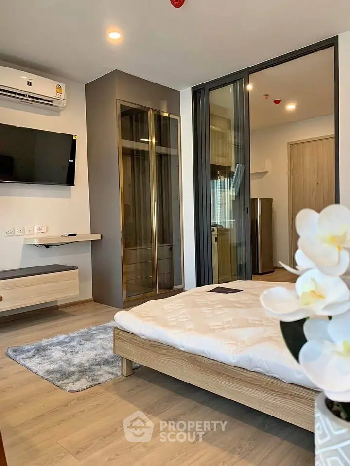 Modern bedroom with sleek design, featuring a wall-mounted TV, air conditioning, and stylish decor.