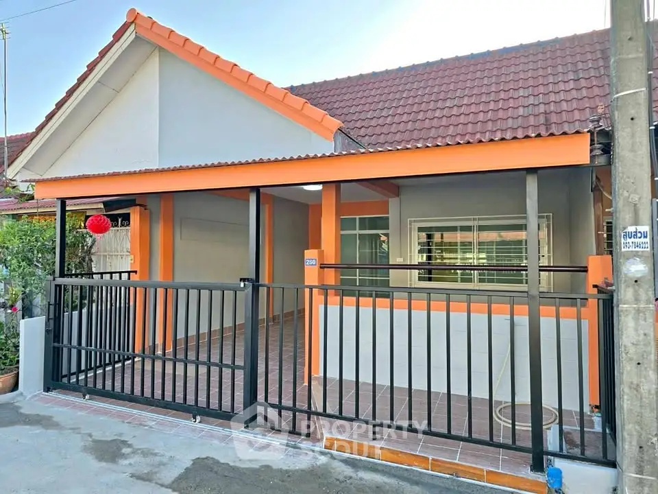 Charming single-story home with orange accents and gated entrance, perfect for cozy living.