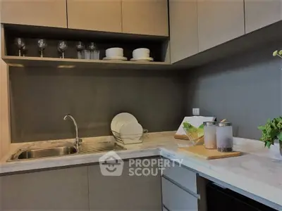 Modern kitchen with sleek cabinetry and marble countertops, featuring a stylish open layout and elegant dishware display.