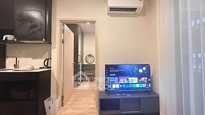 Modern apartment interior with open kitchen and cozy living area featuring a smart TV.
