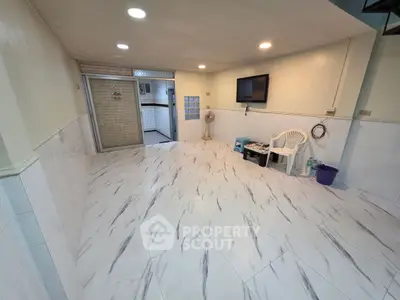 Spacious tiled room with wall-mounted TV and seating area, perfect for versatile use.