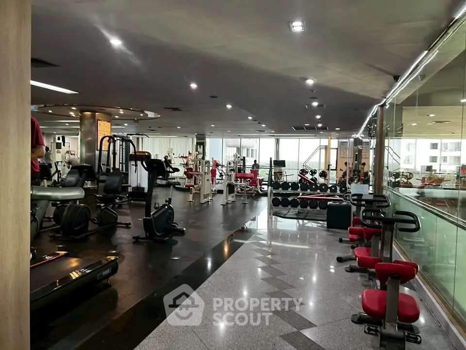 Spacious modern gym with state-of-the-art equipment and large windows for natural light.