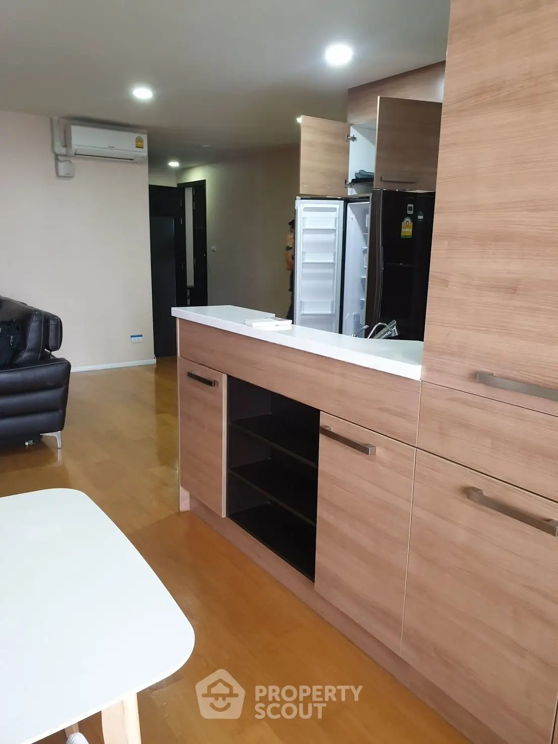 Modern open-plan kitchen with wooden cabinetry and sleek appliances in a stylish apartment.