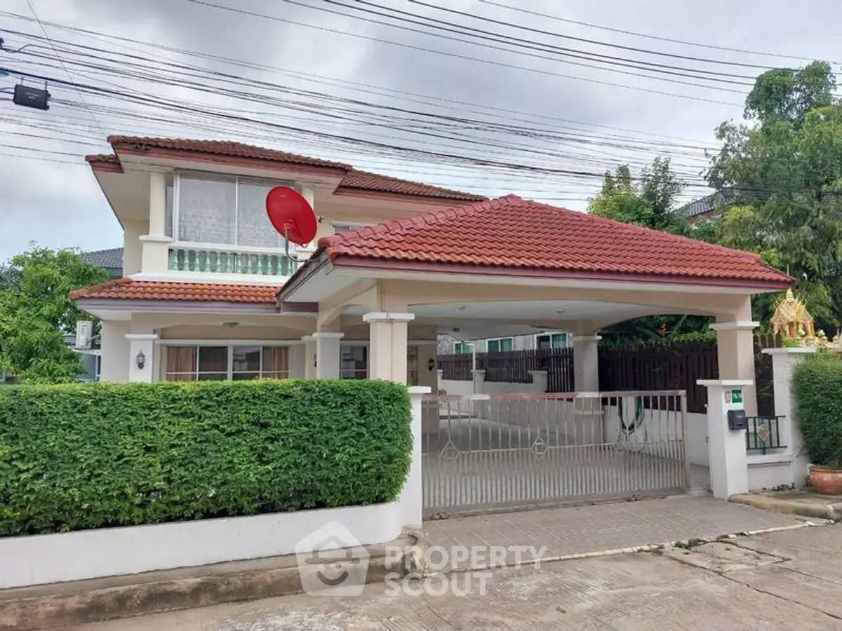 Charming two-story house with red tile roof and lush greenery