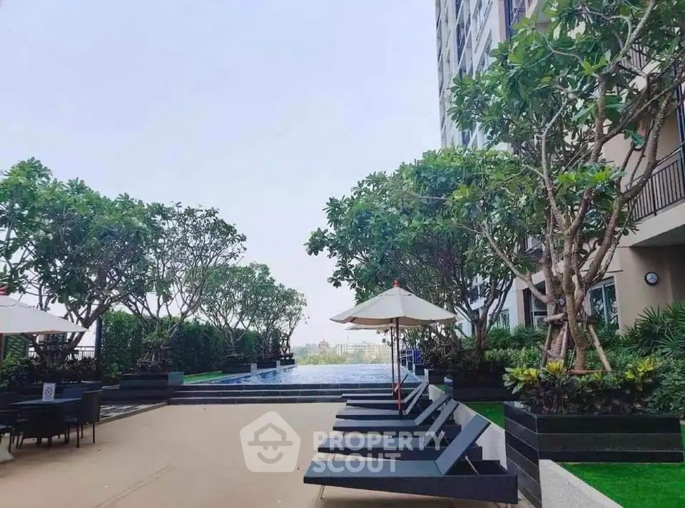 Luxurious rooftop pool area with sun loungers and lush greenery in modern building.