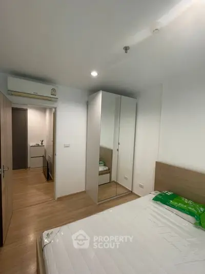 Modern bedroom with mirrored wardrobe and wooden flooring in a stylish apartment.